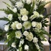 All white funeral spray 
Flowers include snapdragons, hydrangeas, chrysanthemums, and roses