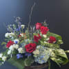 A crystal cross keepsake nestled in bountiful blooms of red, white, and