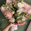 A hand wrapped bouquet of soft color blooms and white florals, with