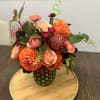 An arrangement of roses, protea and dahlias in a fresh pineapple shell.