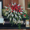 Beautiful tribute full of red roses and white snapdragons with plenty of