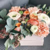 Ranunculus, eucalypus and roses&nbsp;beautifully displayed in a white wooden box.