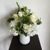 Flower arrangement designed in a white ceramic vase, filled with a mix