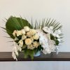 
- Features elegant white roses, delicate orchids, and lush green accent leaves
-