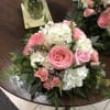 White hydrangeas, pink roses, pink spray roses, pink wax in a floral