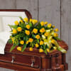 A half couch casket spray of golden roses, solidago and accented with