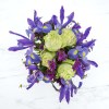 A white box vase, green roses, and vivid blue iris make this