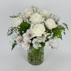 A small arrangement with roses, alstroemerias, dianthus, and greenery in a clear