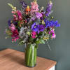 Colorful, tall arrangement filled with seasonal blooms with a lush garden look.