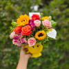 This bright floral arrangement is quite literally a cup of joy! Featuring