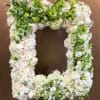 This frame includes white and green roses as well as matching snapdragons.