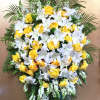 This sympathy spray includes bright yellow roses, stargazer lilies, and seasonal greens.