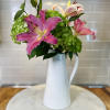 A vibrant mix of Lilies and bright green shamrock hydrangeas. Designed artfully