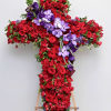 This sympathy cross contains vibrant red roses and purple orchids with touches