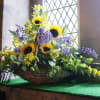 Basket-sunflowers, blue delphinium, yellow filler and mixed greens