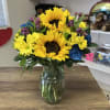 A unique arrangement accenting sunflowers arranged with a combination of bold colored