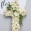 White Cross filled with roses, spray roses and pop of green accents.

We