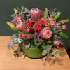 Proteas, lilies, spray roses, fresh greenery arranged in round glass vase

DELUXE IN