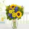 Arrangement filled with yellow daises, sunflowers, blue delphinium, green buttons, and solidago.