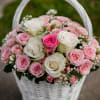A delicate arrangement of light pink roses in a basket exudes beauty