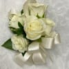 A wrist corsage made with white spray roses,simple green, and accent with