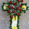 Cross with red roses, yellow mums, and white carnations.