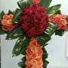 Cross with orange roses and red roses.
