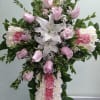 Cross with pink and white carnations, pink roses, and white lilies.