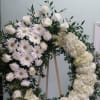 Open wreath with white gerbera daisies, carnations, roses, and hydrangeas.
