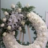 Open wreath with white roses, daisies, and lilies.