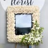 This white sympathy frame is made with all white roses and a