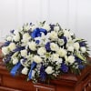 A beautiful white casket spray with a pop of blue Delphinium 