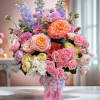 This elegant floral arrangement features delicate roses in soft pastels, vibrant delphiniums