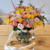 A vase filled with peach and yellow roses radiates elegance and warmth.The