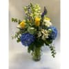 Tall clear vase  with blue hydrangeas, white snapdragons, yellow roses, white
