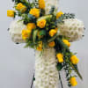 The funeral arrangement features a solemn cruz adorned with delicate white flowers