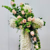 The funeral arrangement highlights a reverent cruz accentuated by soft white blooms