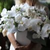 Orchids with mix of flowers in a tall vase