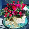 designed in a gold square vase, with red roses, magenta carnations, red