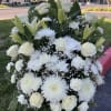 A fan shaped floral arrangements of all white flowers including dahlias, roses