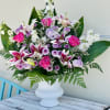 This Beautiful sympathy arrangement includes star gazer lilies, purple and pink roses