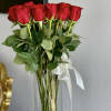 Two Dozen long stemmed red roses stand tall in a glass cylinder