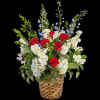 A red, white, and blue tribute flower basket featuring red roses, blue