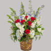 A red, white, and blue tribute flower basket featuring red roses, blue