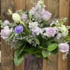 The arrangement features a rich variety of purple flowers, creating a visually