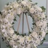Open wreath with white roses, mums, daisies, and stock.