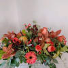 A rustic wooden box filled wit a burst of autumn, pumpkin,orchids,roses, leaves