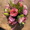 This arrangement includes garden roses, lilies, green foliage all hand arranged in