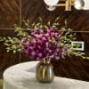 A chic arrangement of fresh-cut Dendrobium orchids in a sleek gold vase