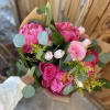 A hand wrapped bouquet of hot pinks and soft pink fresh blooms